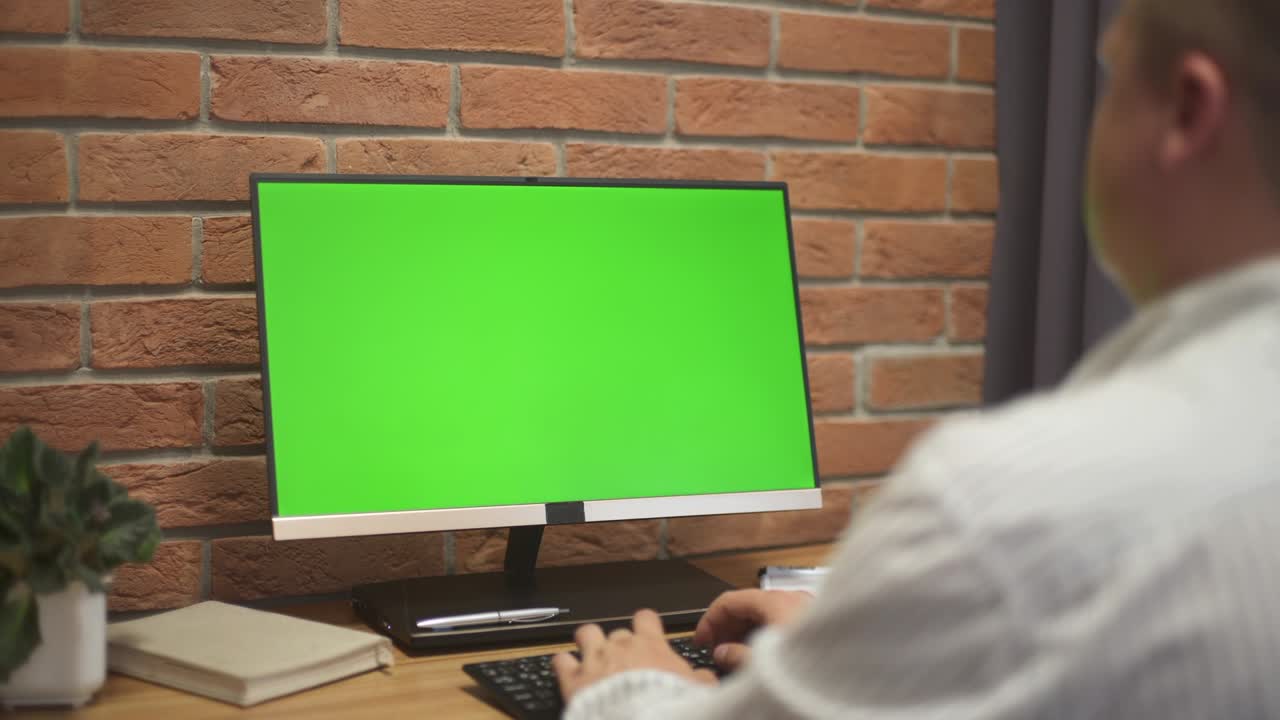 hombre trabaja en la computadora personal con pantalla de maqueta verde en la oficina
