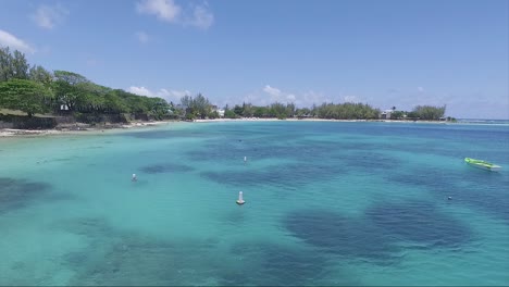 Crystal-clear-beach-waters-of-the-island-of-Mauritius-on-vacation,-with-a-empty-stationary-motor-boat-and-floaters