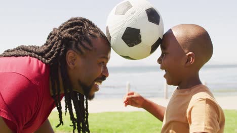 video of happy african american father and son having fun with ball outdoors