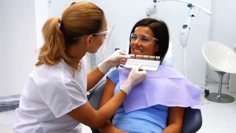 dentist examining female patient with teeth shades