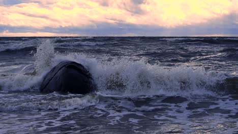 Waves-in-the-sea-during-a-thunderstorm-at-sunset,-large-stones-on-the-sea-shore