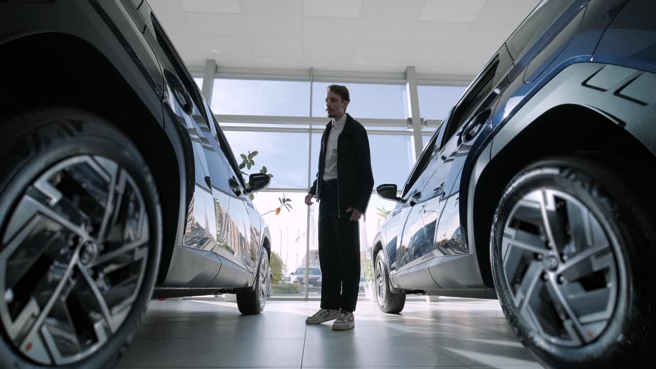 Man looking at new cars in dealership showroom