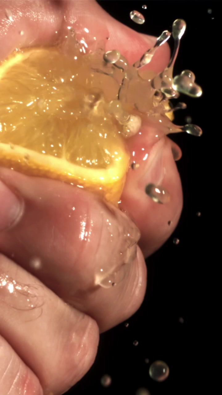Nærbillede af hånd, der presser frisk citronsaft i slowmotion