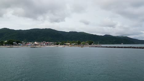 Establishing-Aerial-View-of-a-calm-ocean-bay-leading-to-coastline-of-idyllic-rural-island-town