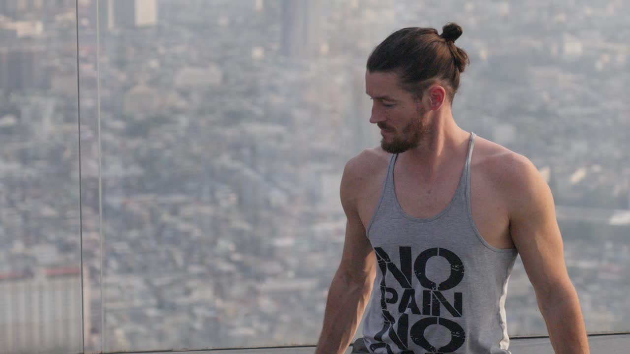 middle aged caucasian man looking through glass enjoying the view on the Bangkok, Mahanakhon skytower.