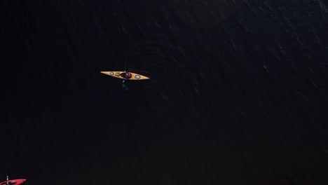 Rising-drone-shot-of-two-kayakers-floating-on-dark-murky-water