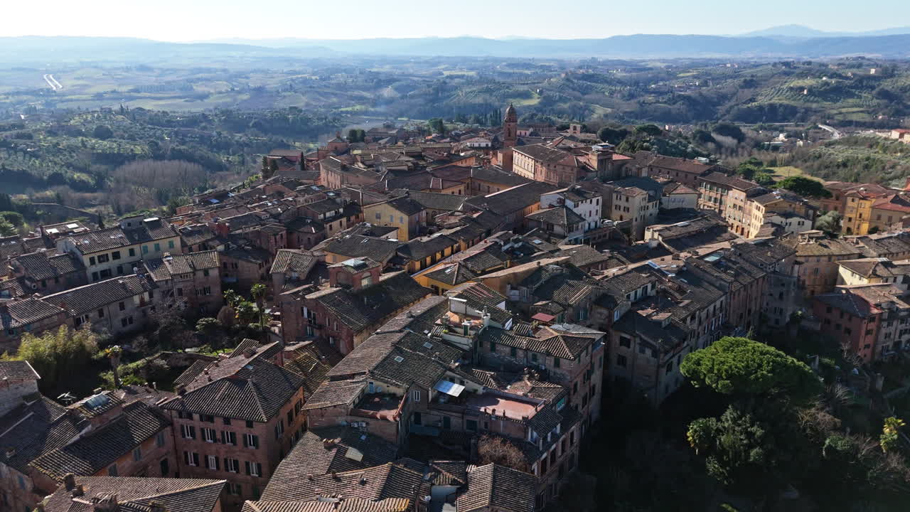 Medieval Italian town with terracotta rooftops and scenic countryside in Siena