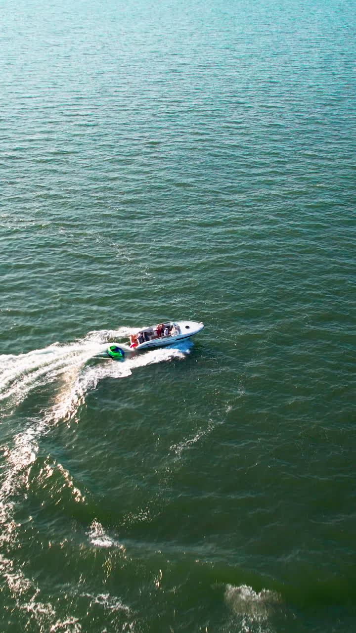 Aerial view of a white motorboat speeding across the open sea, creating white foam waves. Perfect for travel, vacation, and maritime lifestyle content
