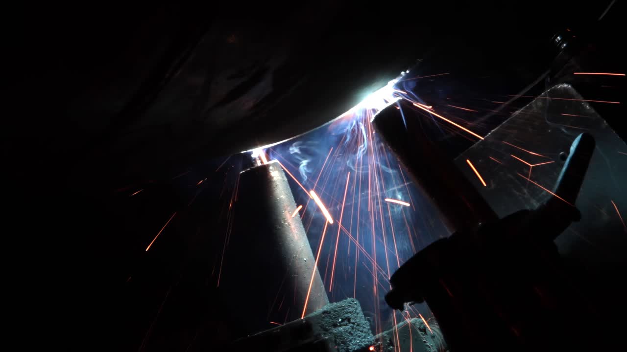 Industrial welding robot working with metal Sparks smoke and bright light from robotic welding arm Automated factory process Manufacturing and technology concept No people