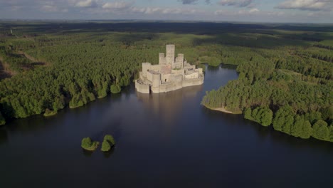 aerial orbit shot of the beautiful castle of stobnica, poland - a big tourist attraction built on an artificial island on a lake in the middle of an unhabituated forest