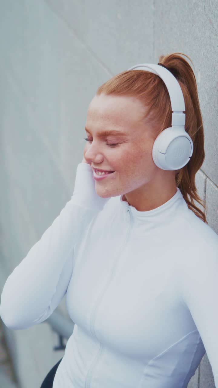 Una giovane donna concentrata che si gode la musica con cuffie wireless mentre usa il suo smartphone, catturata in due fotogrammi che mostrano connettività e facilità.