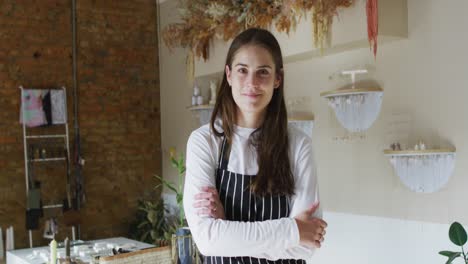 smiling caucasian waitress with crossed hands, wearing striped apron looking at camera