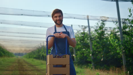 agronomist man looking camera in fruit orchard. farmer show harvest in garden.