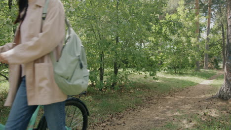 woman walking bicycle through forest