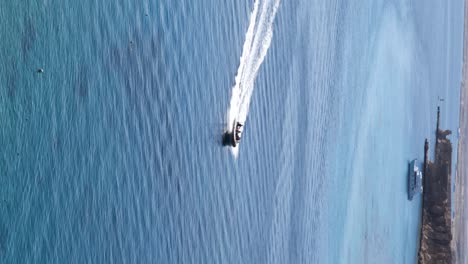 Speedboat-full-of-people-crusing-trhough-the-sea-with-rocks-in-background