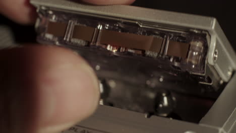 microcassette recorder cassette being inserted and record button being activated with reels in motion visible