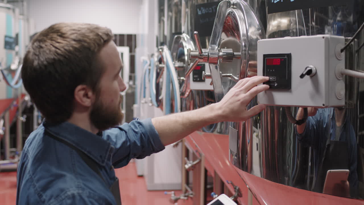 Male Brewery Worker Setting Parameters On Brew Equipment