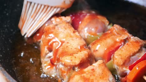 chicken kebabs being brushed with sauce