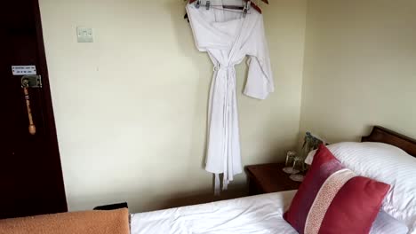 incline hacia arriba la vista interior de la habitación del hotel con cama doble, llavero africano y albornoz, día
