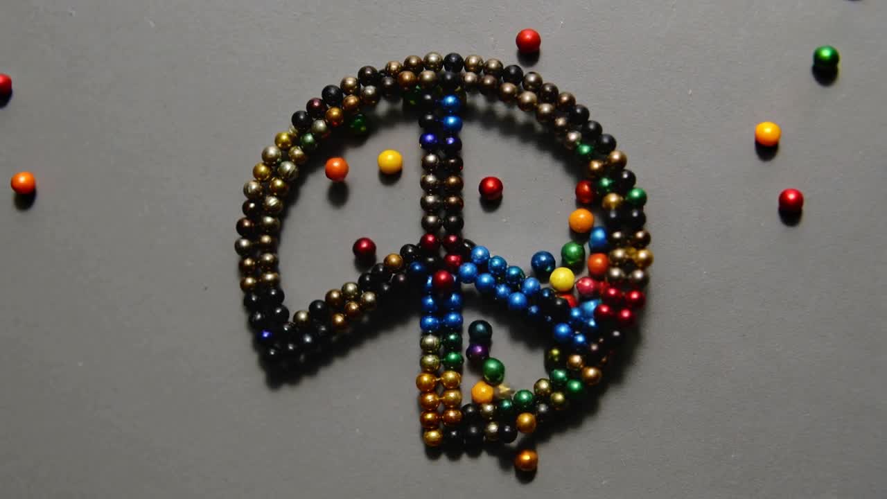 Formare perline magnetiche colorate in un emblema circolare con raggi su un tavolo grigio, con ombre.
