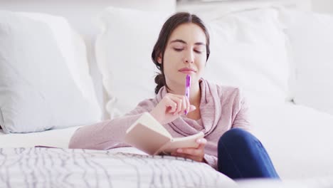 mujer caucásica feliz sentada en el suelo y tomando notas