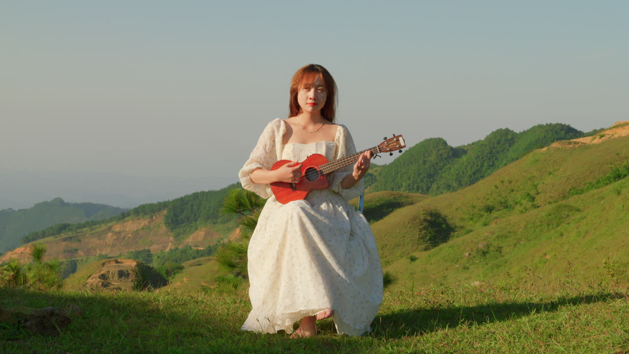 young asiatic hippie style girl red hair playing acoustic guitar in nature