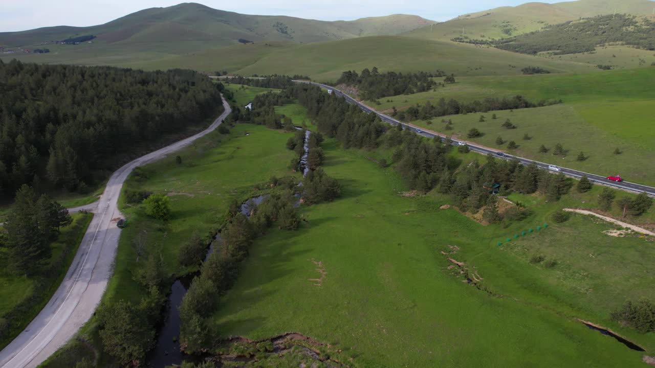 Zlatibor, Serbia. Drone Shot of Idyllic Green Mountain Landscape, Creek and Meadows Between Roads on Sunny Summer Day