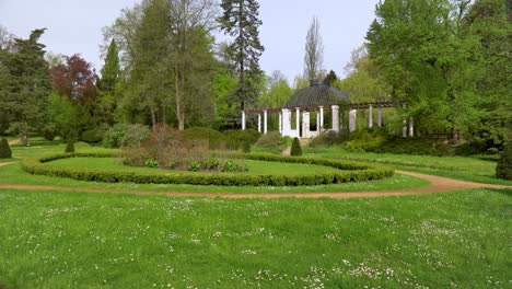 beautiful european garden with tidy beds and a summer house on a sunny day