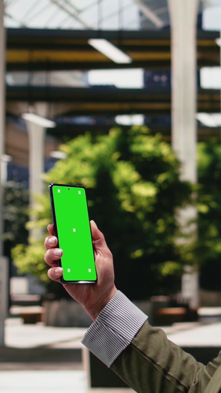 Video verticale: dispositivo smartphone con chroma key utilizzato da un viaggiatore d'affari nella stazione degli autobus.