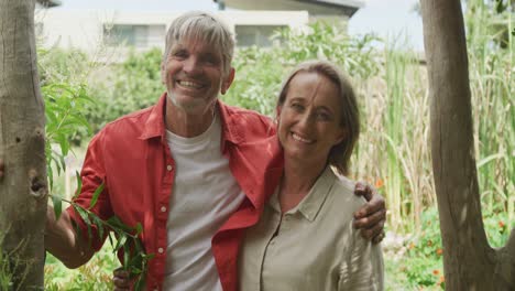 portrait of smiling senior caucasian couple embracing in garden