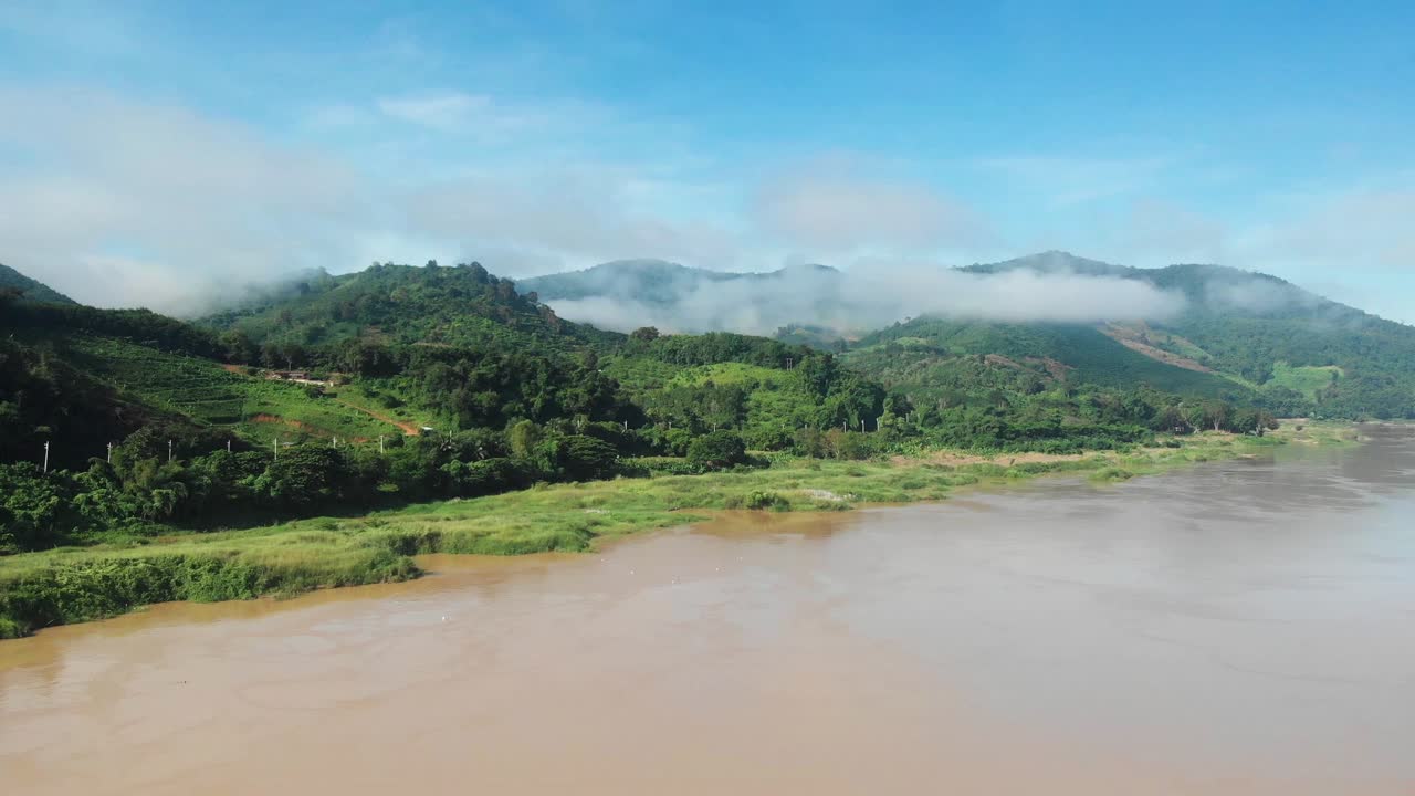 Montagne avvolte dalle nuvole lungo un grande fiume, il fiume Mekong al confine tra Thailandia e Laos