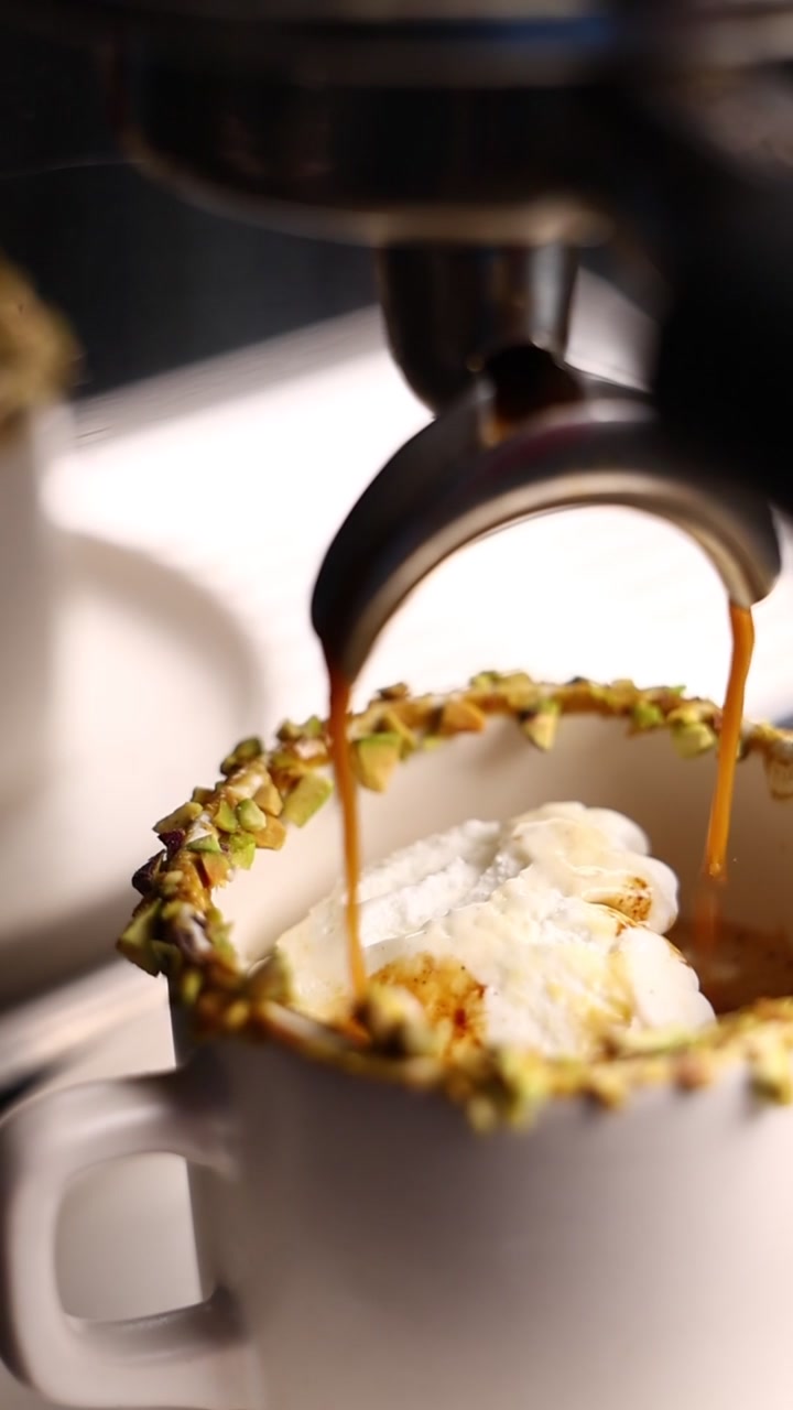 Espresso versato su gelato in una tazza con bordo al pistacchio
