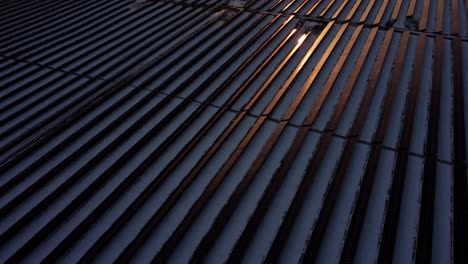 flying over the snow-covered solar panels field in canada, bathed in reflective orange light