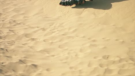 Gypsy-woman-walking-and-holding-her-dress-on-a-desert-sand-dune