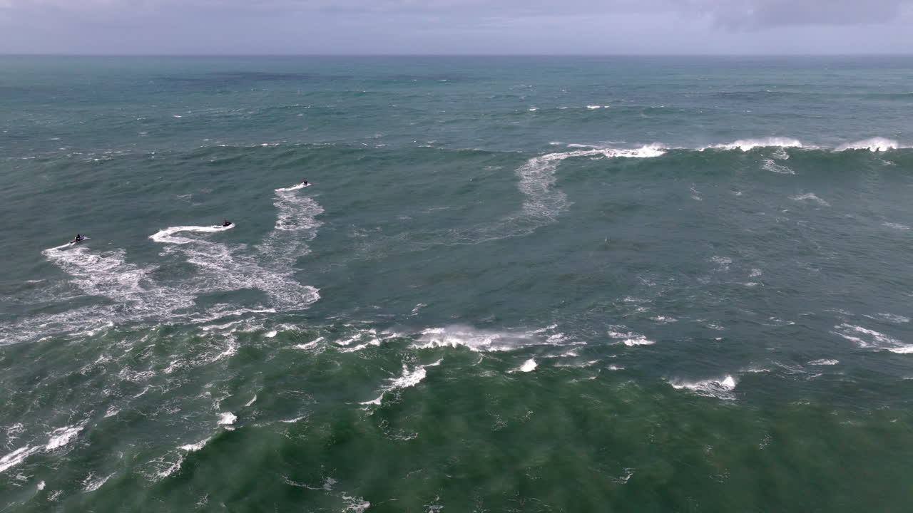 Jet ski operators crossing famous iconic Nazaré waves. Aerial drone shot