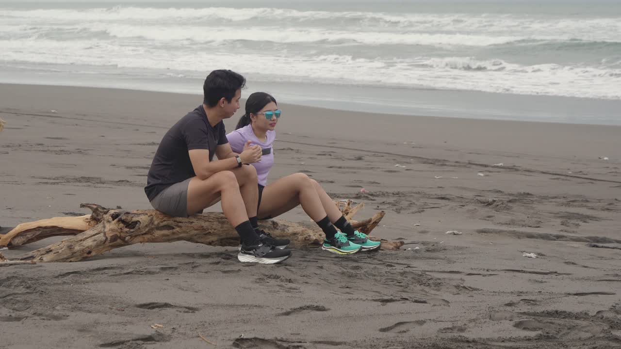 Couple relaxing on driftwood at the beach