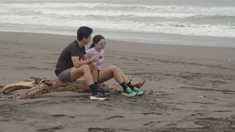 couple relaxing on driftwood at the beach