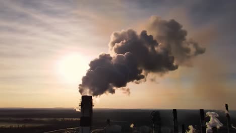 dramatic contrast of industrial emissions against a sunset landscape: observing the environmental impact of smoke from factory chimneys