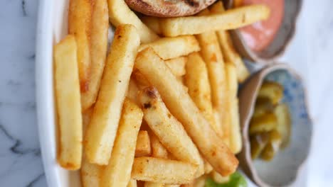 close-up of golden french fries and a burger with condiments