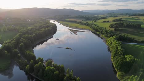 Ein-Blick-Auf-Einen-Breiten-Fluss-Und-Eine-Eisenbahnbrücke,-Die-Ihn-Aus-Großer-Höhe-Bei-Sonnenuntergang-Auf-Dem-Land-überquert