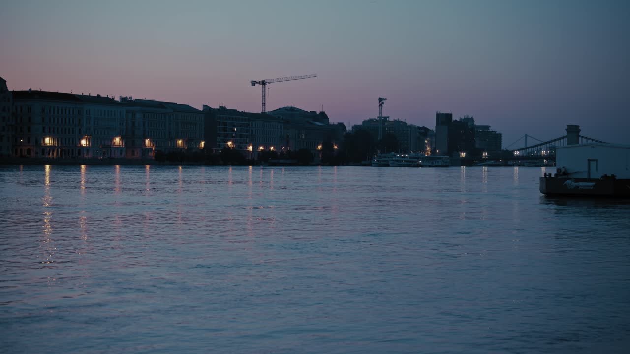 Riverside buildings reflecting on calm water at dusk during the 2024 flood in Budapest