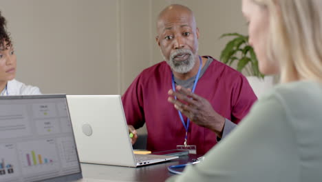 diverse doctors using laptops in meeting room with copy space, slow motion