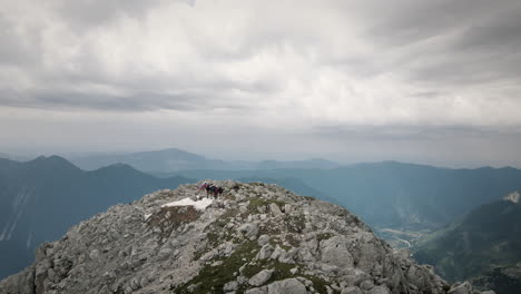 Drone-shot-around-the-top-of-moutani-Rombon-on-which-stands-a-group-of-hiker-with-a-slovenian-flag