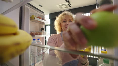 a woman looking inside a fridge