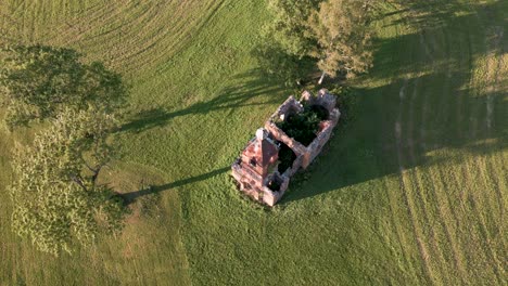 fast flyover lost place church ruin without roof in estonia, europe - aerial drone flight over orange sandstone building that looks like a tiny orthodox or catholic church on a green meadow, 2022