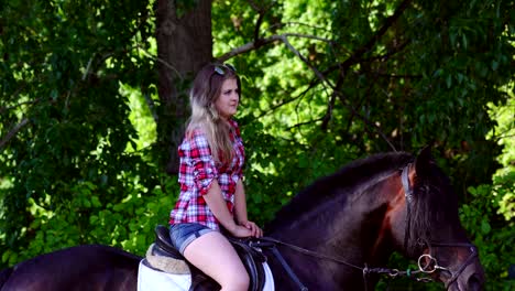 young blonde woman in a plaid shirt takes a walk with his horse. summer sunny evening.