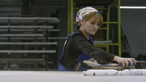 woman sanding wood panel in a factory