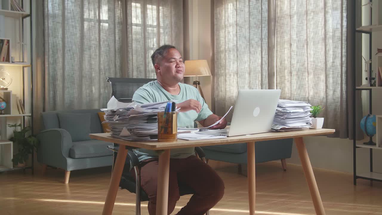 Fat Asian Man Having Video Call On Laptop While Working With Documents At The Office