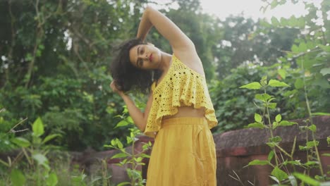 Woman-in-nature-yellow-outfit-fashion,-flips-and-caress-hair-seductively