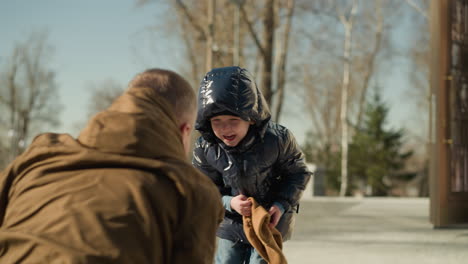 a father and son playing as the son drags the fathers brown beanie from his head as both of them began to laugh been excited